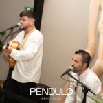 Dúo acústico cantando con guitarra y micrófonos en un evento interior
