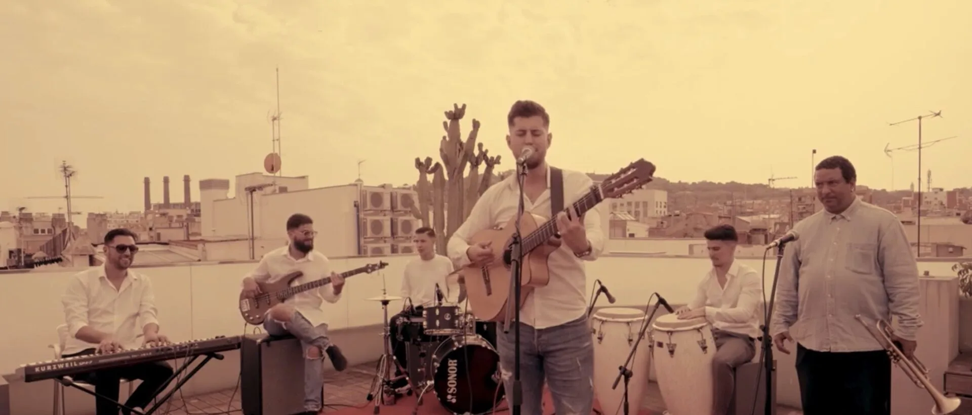 Grupo tocando música en directo en una azotea al atardecer